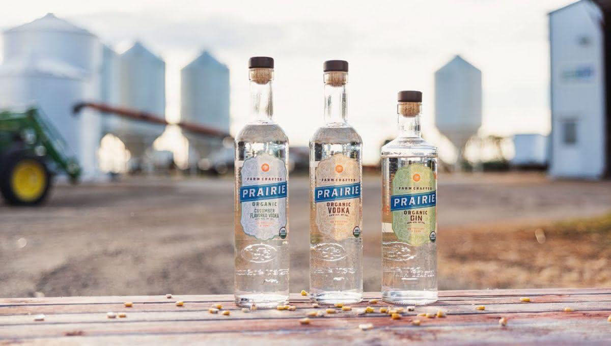 three bottles of vodka in front of farm silos